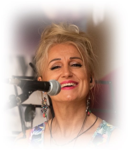 Gyurász Ildikó közeli portréja, mosolyogva a mikrofon előtt